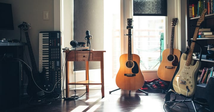 A room with electric guitars, wooden guitars, keyboard or piano, a headset, and a mike.