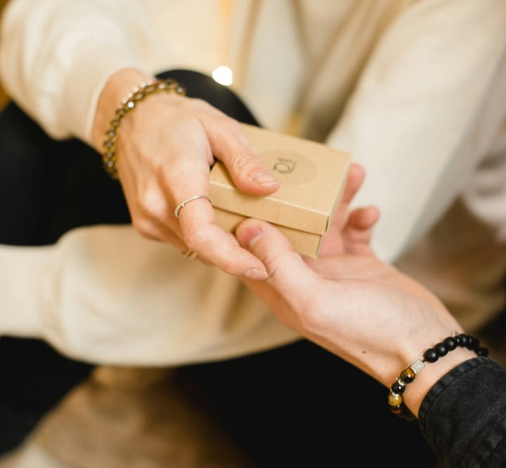 One person handing a gift to another person.