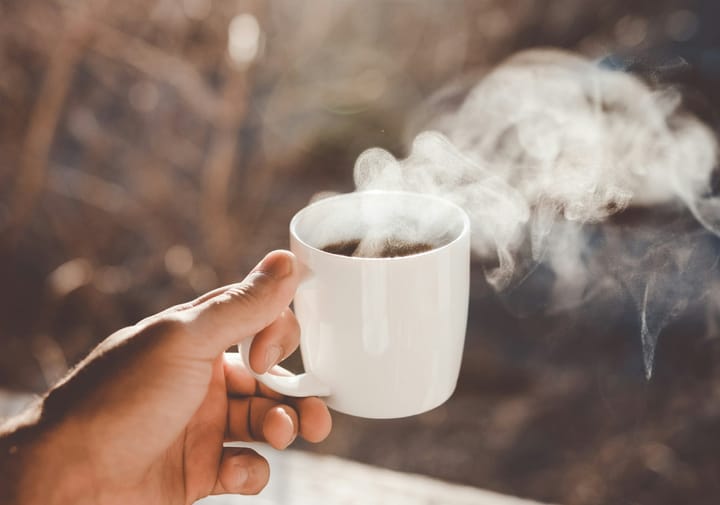 Hand holding a steaming coffee